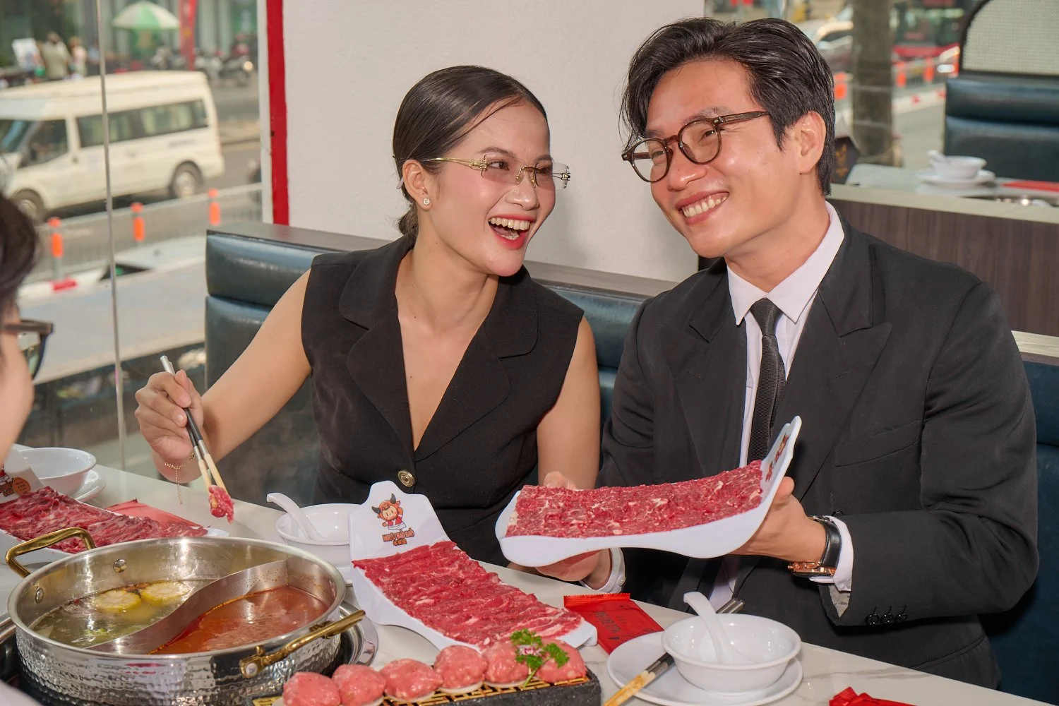 Nhóm dân văn phòng lịch sự đang mỉm cười dùng bữa lẩu trưa ấm cúng trong không gian nhà hàng sang trọng
