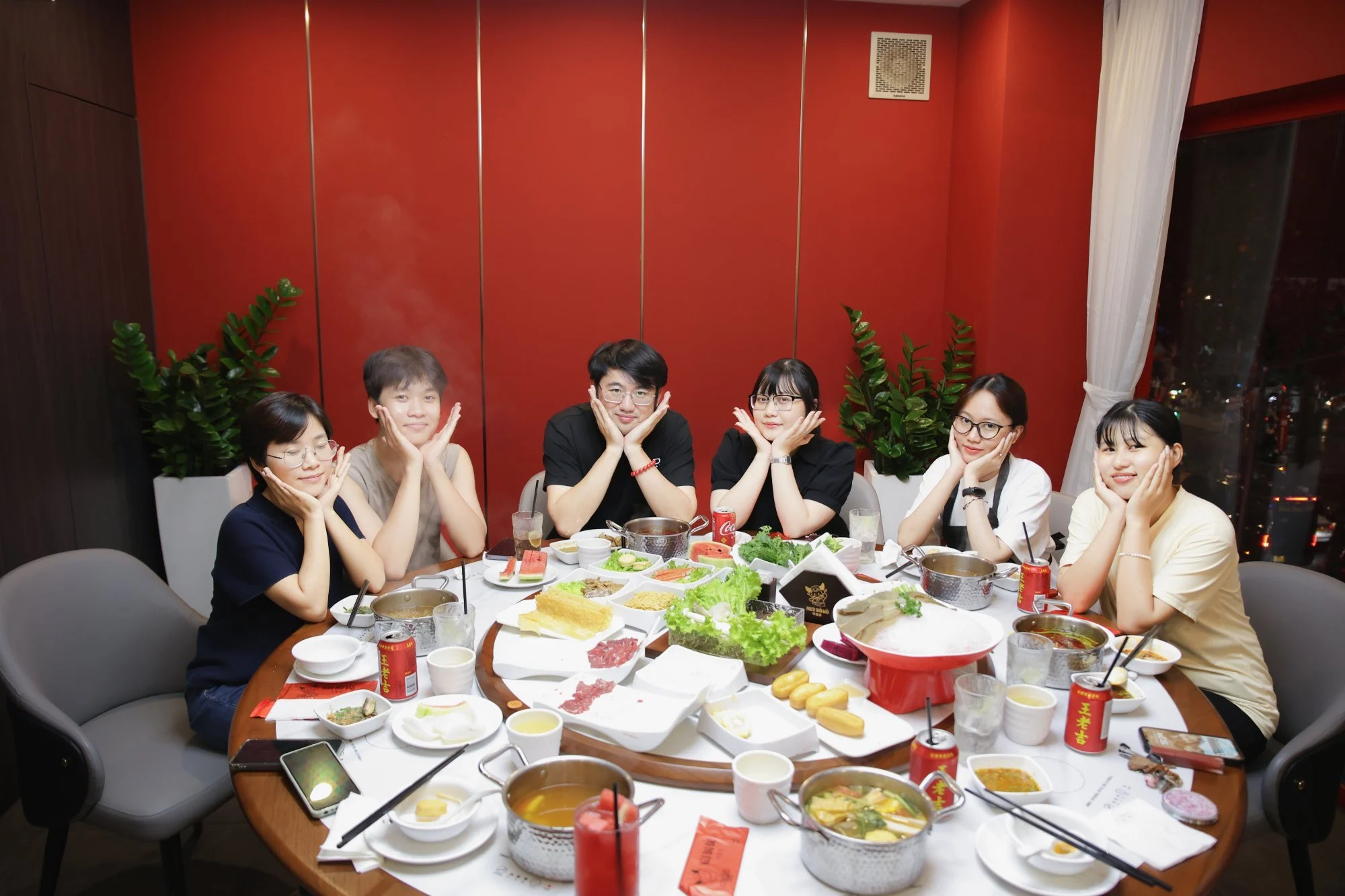 Nhóm bạn bè tươi cười nâng ly nước thanh mát, ánh mắt rạng rỡ quanh nồi lẩu bò Triều Châu nghi ngút khói trong không gian nhà hàng sang trọng